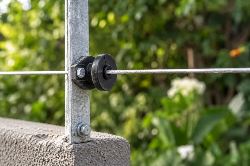 Close-up of a cracked black electric-fence insulator supporting a single wire
